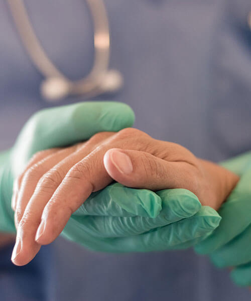 A doctor wearing gloves holding a patient's hand